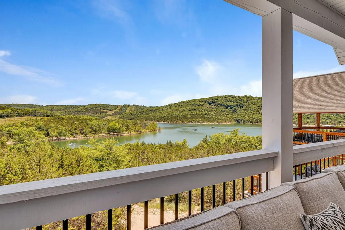 A serene view of Table Rock Lake with surrounding hills and comfortable deck furniture in the foreground. The image radiates calm, with the lake stretching into the distance and inviting outdoor seating positioned to take in the natural scenery.