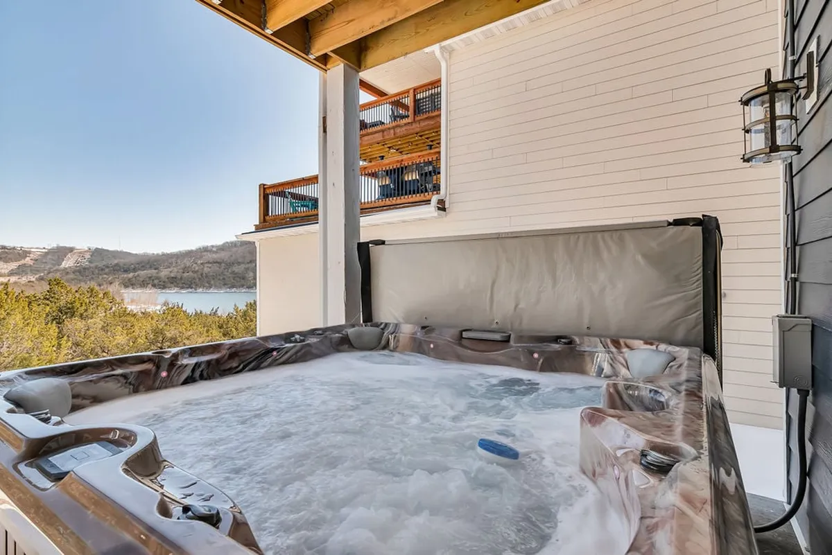 An inviting exterior shot of a private hot tub set on a deck, overlooking a peaceful landscape. The scene is serene, emphasizing relaxation and scenic enjoyment, with room for guests to unwind together.