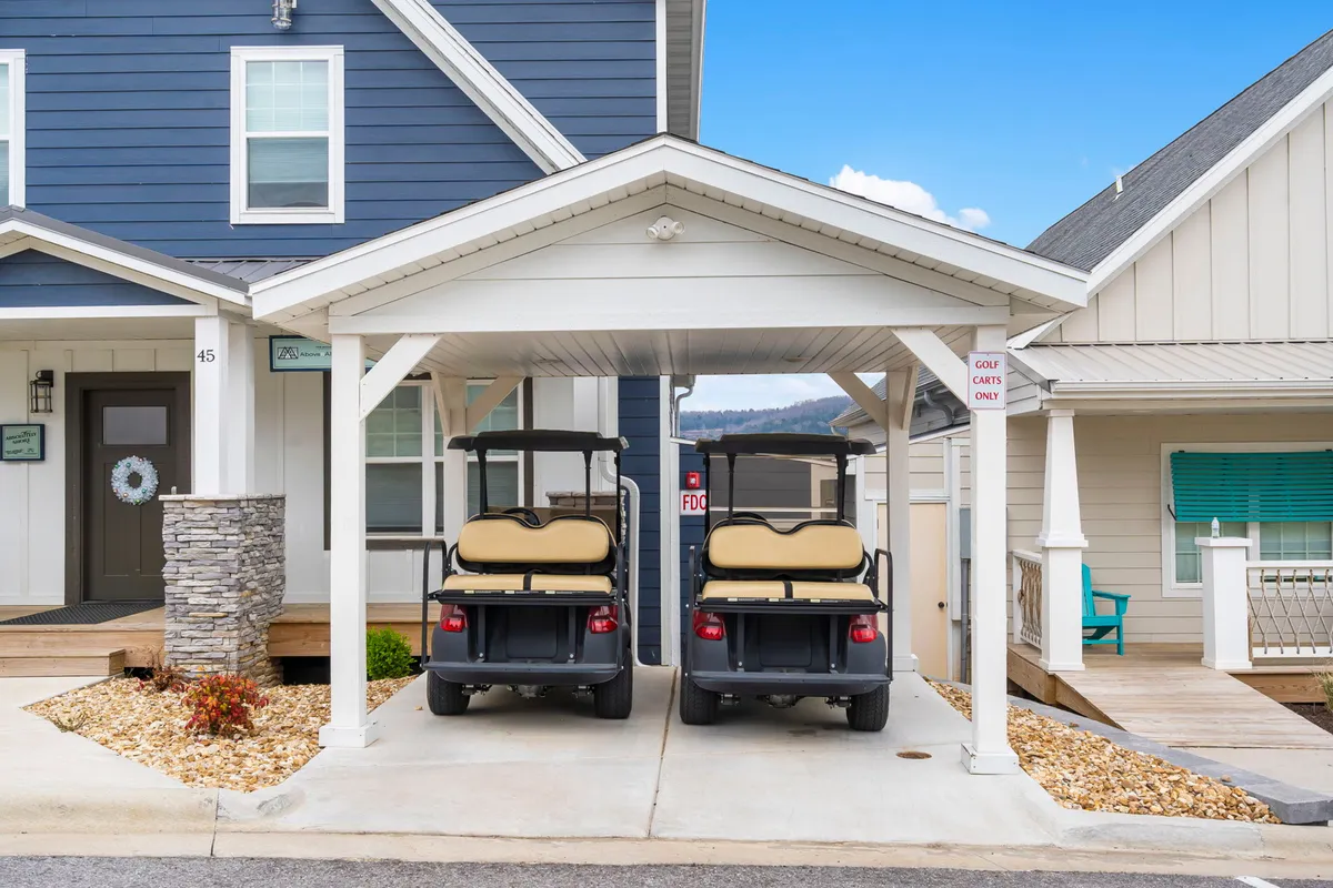 An exterior shot of golf carts parked beside a stone pillar and front door, suggesting ease of access and convenience for guests. The relaxed setting hints at leisurely exploration and resort mobility.