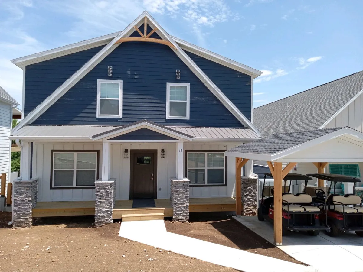 The main entrance to the property features stone columns, a golf cart parking area, and an inviting porch. The landscape hints at outdoor fun and easy access to local amenities and trails.