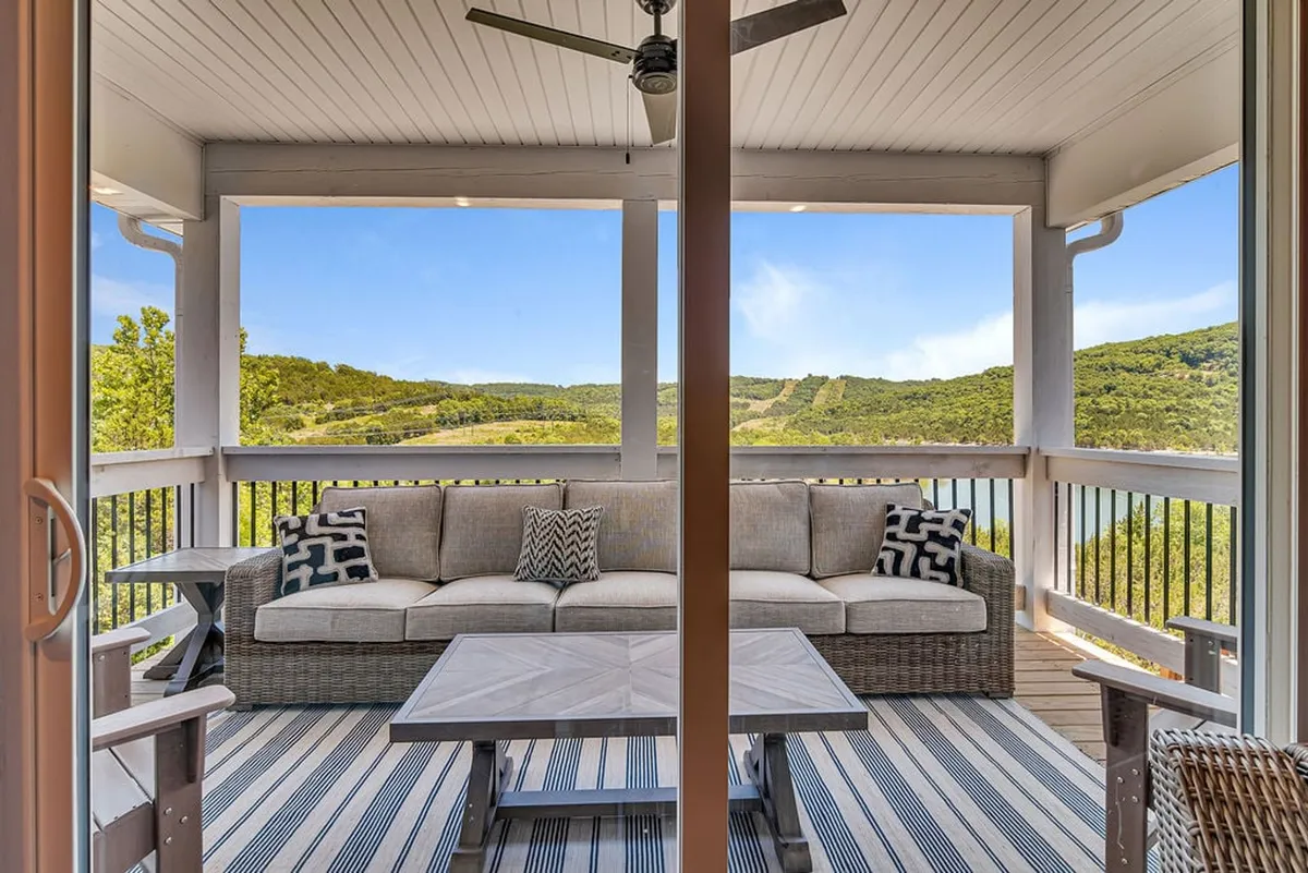 A tranquil outdoor living space with a spacious sectional sofa on a patio or deck, set against a backdrop of scenic mountains. The area is designed for relaxing and soaking in natural beauty, highlighting retreat and comfort after a day of adventure.